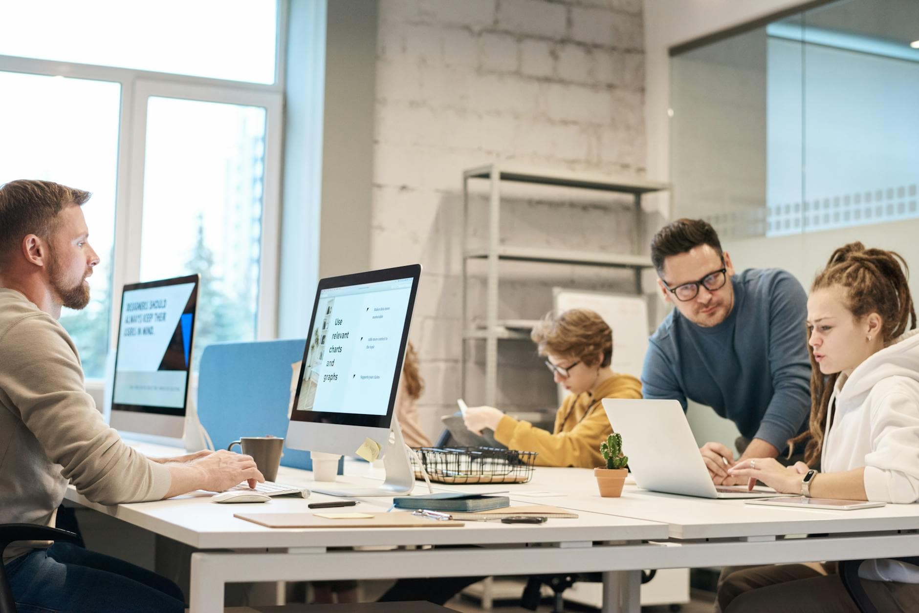 Office workers sitting at a table, looking at computer screens